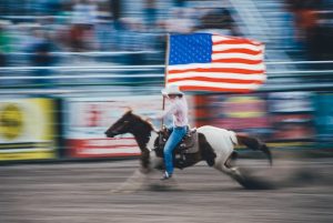 man riding a horse holding the american flag